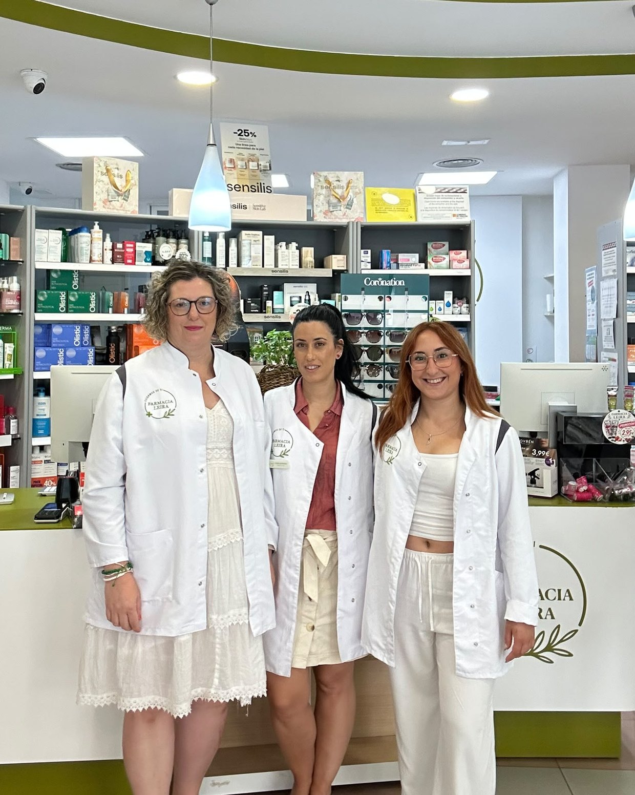 El equipo de Farmacia Leira, con bata blanca, junto al mostrador de la farmacia en Huesca.